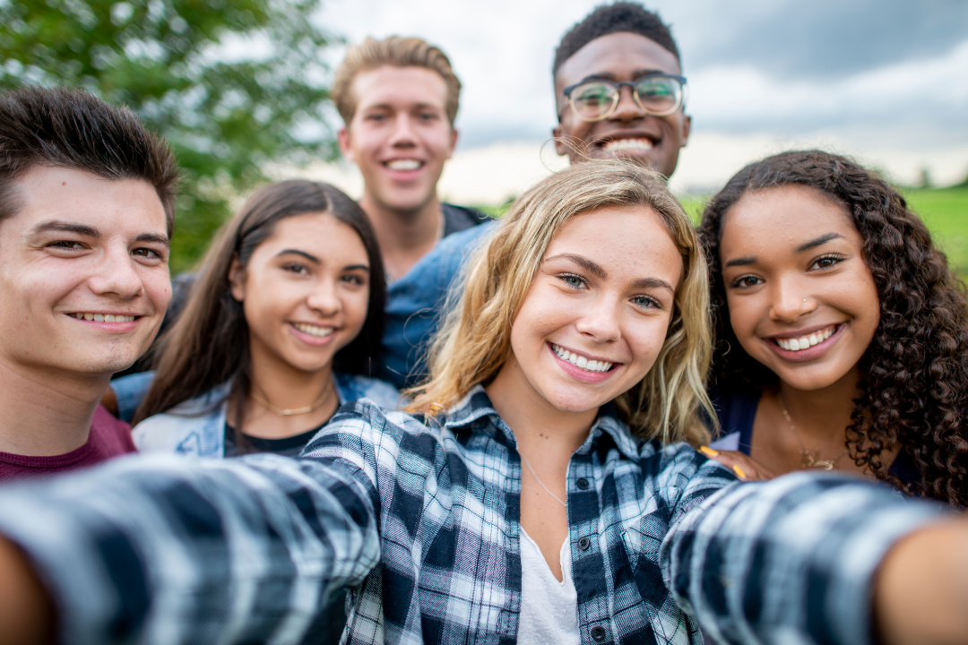 A picture of six teens, heads close together, for a selfie.