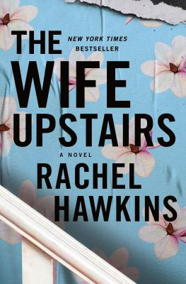 The Wife Upstairs book cover. The background is blue wallpaper with white flowers, and a white bannister is running down the bottom left corner. The title is written in black letters.