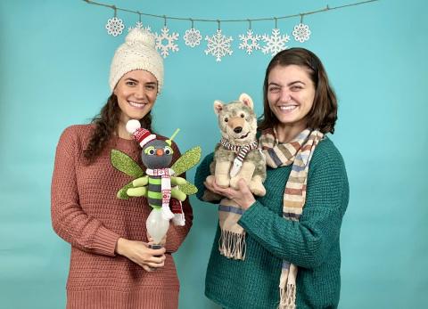 Two women holding a wolf puppet and a firefly puppet