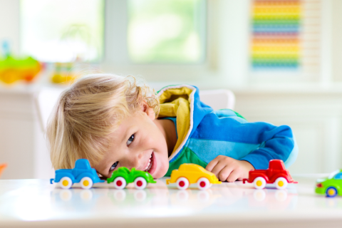 little blonde white boy playing with toys cars