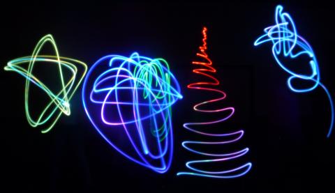 light drawing of a yellow star, purple squiggle, red christmas tree, and blue squiggle