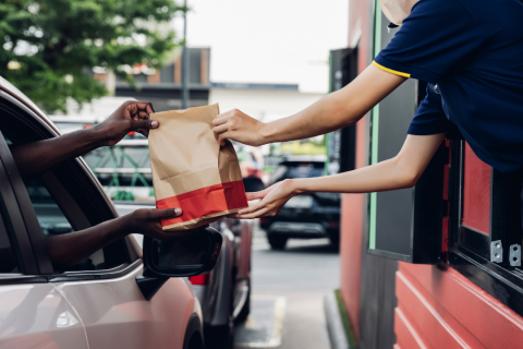 The passing of a fast food back from the restaurant employee to the customer in their car.