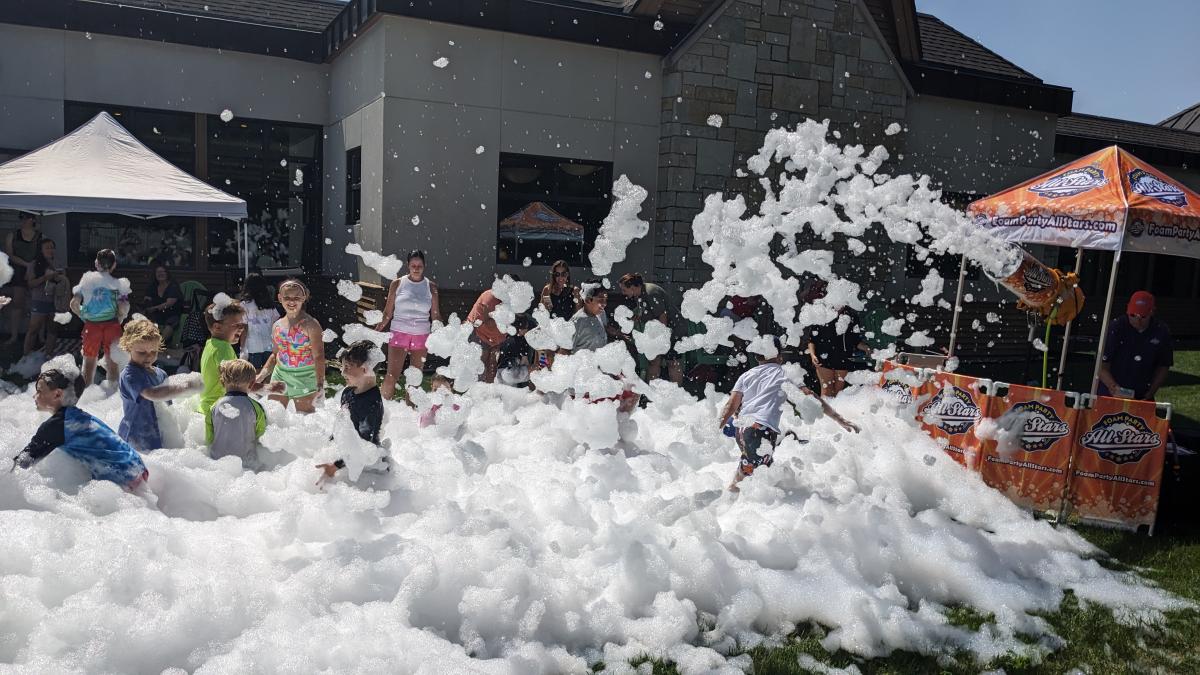 A large amount of foam with a bunch of children playing in it. 