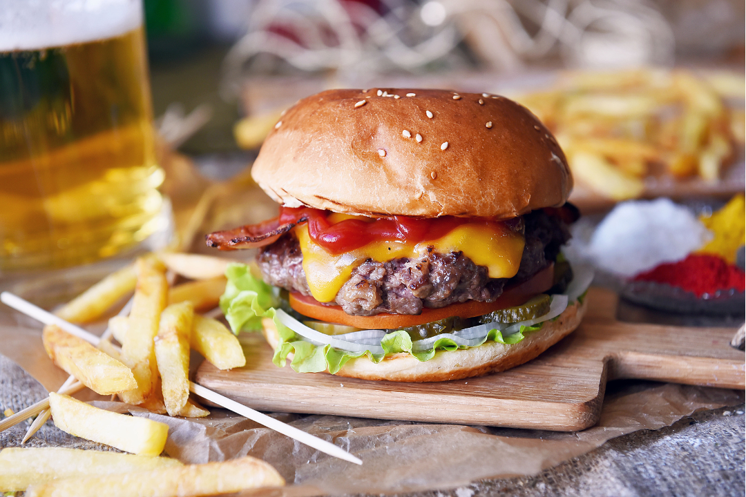 A picture of a burger with lots of toppings next to a pile of fries.