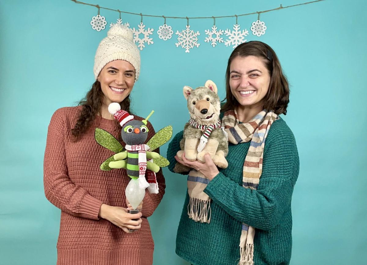 Two women holding a wolf puppet and a firefly puppet